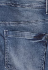 Denimová tkanina ve světle modré barvě s hladkým povrchem, obsahující zadní kapsu a viditelné švy. Klasický pětikapsový design.