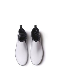 Bottines blanches à la finition brillante, avec des côtés élastiques et un revêtement intérieur noir. Dotées de tirants pour un enfilage facile. Forme lisse et épurée.
