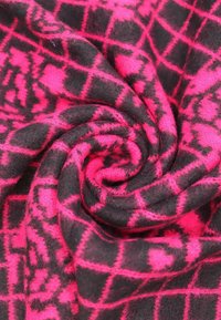 Tessuto in pile nero e rosa neon, con motivo a quadri. Texture morbida, con un contrasto di colori vivace e dettagli di cucitura visibili.