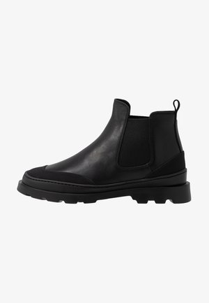 Black leather Chelsea boots with elastic side panels, round toe, and textured rubber sole. Features a pull tab for easy wear.