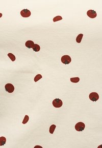 Κόκκινες ολόκληρες και κομμένες ντομάτες διασκορπισμένες σε μοτίβο σε μπεζ υφασμάτινο φόντο με πράσινους ανθούς ντομάτας.