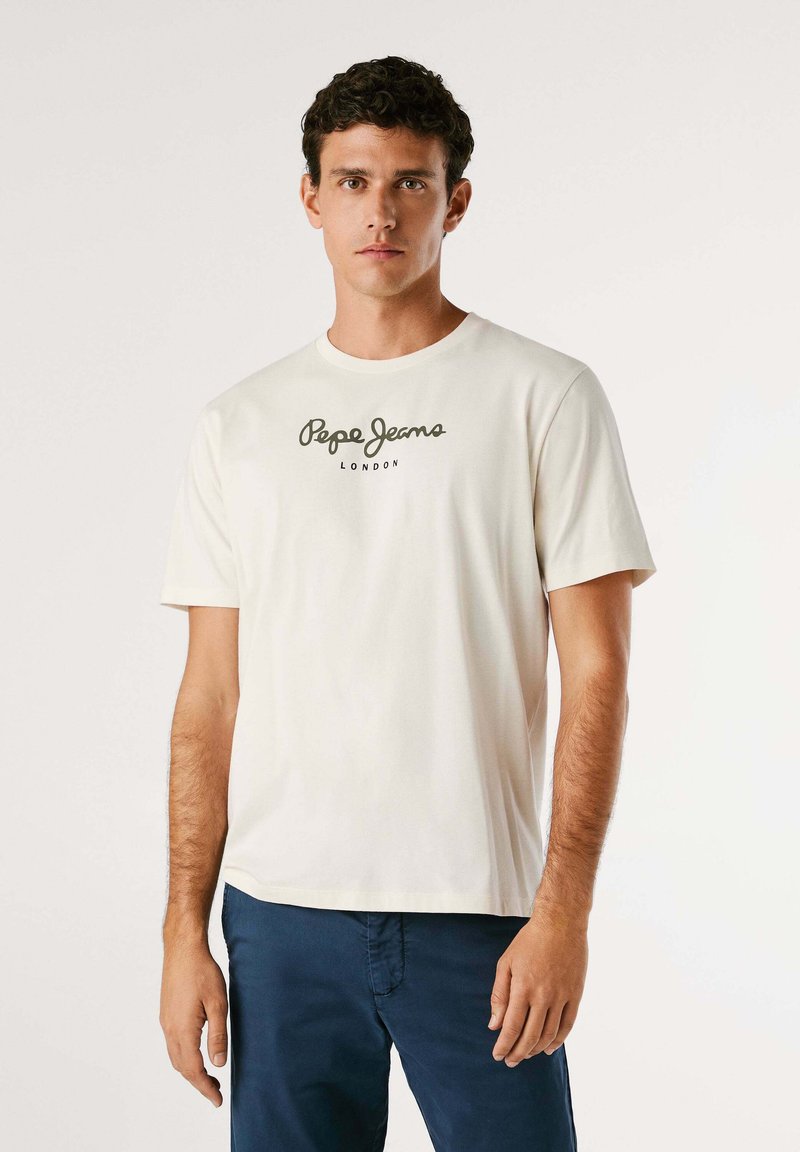 T-shirt crème à manches courtes en coton avec un col rond ; arbore un logo noir "Pepe Jeans London" imprimé sur la poitrine.