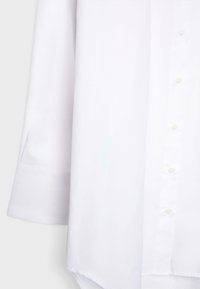 White long-sleeve shirt with buttoned cuff and front button placket, made from smooth fabric.