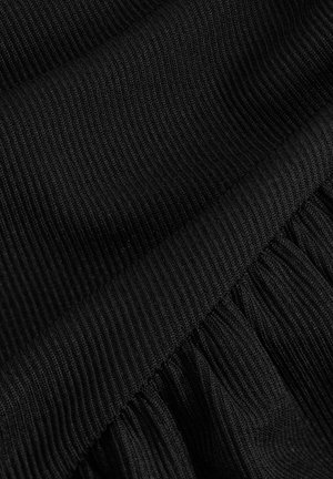 Tessuto di maglia nera che mostra una texture a costine nella parte superiore e dettagli arricciati nella parte inferiore, enfatizzando i livelli e la profondità.