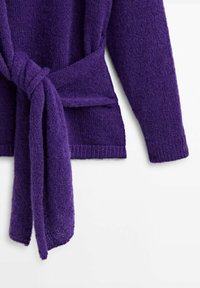 Cardigan à manches longues en tricot violet avec une large ceinture auto-nouée autour de la taille, présenté sur un fond blanc.
