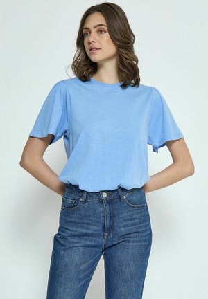 T-shirt bleu clair à manches courtes avec un col rond et une texture subtile, associé à un jean taille haute bleu foncé.
