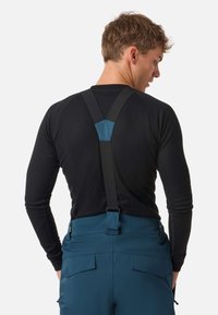 Maglietta nera a maniche lunghe con texture a coste abbinata a pantaloni da sci blu con bretelle regolabili e tasche posteriori.