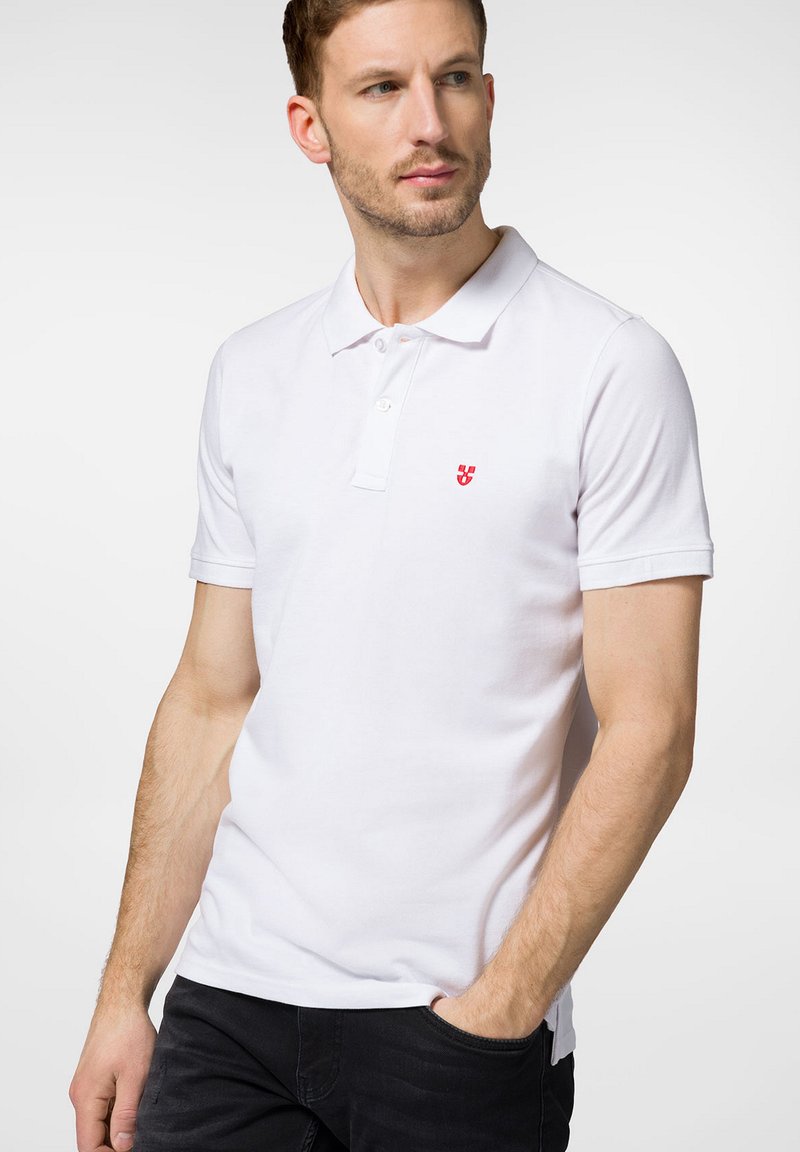 Biała koszulka polo z krótkimi rękawami, trzema guzikami oraz małym czerwonym logo po lewej stronie klatki piersiowej. Miękki materiał bawełniany.