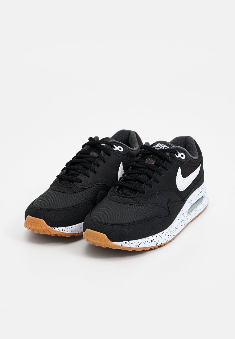 Zwarte sport sneakers met een textuur bovenkant, witte Nike swoosh logo, gespikkelde witte tussenzool en een rubberen zool van gom.