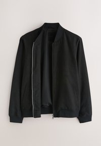 Veste bomber noire décontractée avec fermeture éclair à l’avant, col, poignets et taille côtelés, montrée ouverte sur un fond clair.