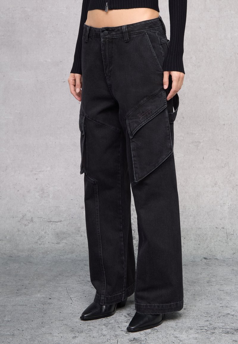 Pantalones cargo negros con piernas anchas, múltiples bolsillos, detalles de costura y un ajuste relajado. Fabricados en tela de mezclilla con un acabado desgastado.