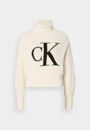 Kerman neulepusero, jossa on korkeakauluksellinen muotoilu ja lyhyt helma. Edessä suuri musta "CK" -logo. Pehmeä neulottu materiaali, pitkät hihat.