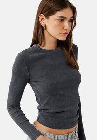 Langsleeve geribbelde top in donkergrijs, met een ronde halslijn en een aansluitend ontwerp, gemaakt van zachte, gestructureerde stof.