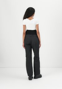 Zwarte broek met een hoge tailleband, met een losse pasvorm en platte zakken. G gedragen met een aansluitend wit shirt met korte mouwen.