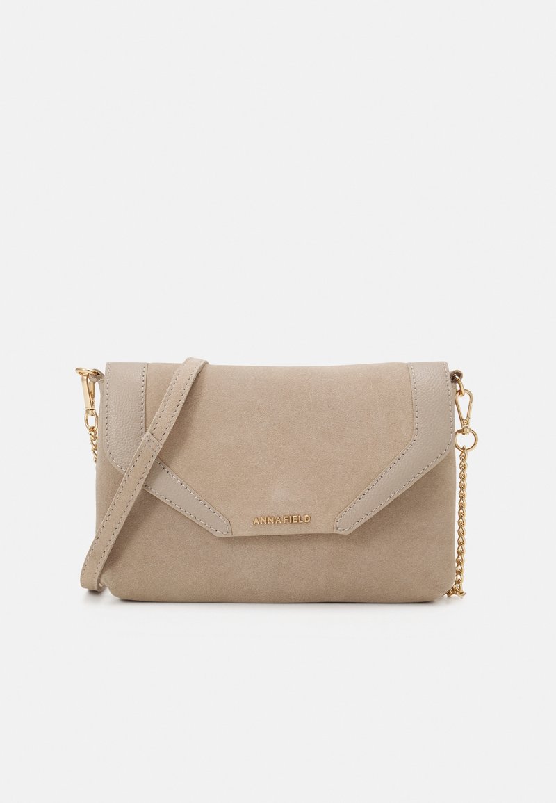 Petit sac bandoulière en daim beige avec rabat, bandoulière chaîne dorée et logo ANNA FIELD au centre devant.