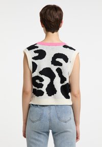Neule sweater ilmanhihoilla, jossa on vaaleanpunainen ribbikolla, mustavalkoinen abstrakti eläinkuos. Teksturoitu kangas, lyhennetty malli.