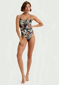 Un maillot de bain une pièce avec une base noire ornée de motifs floraux tropicaux dans des tons de rose et de vert. Design à bretelles et coupe ajustée.