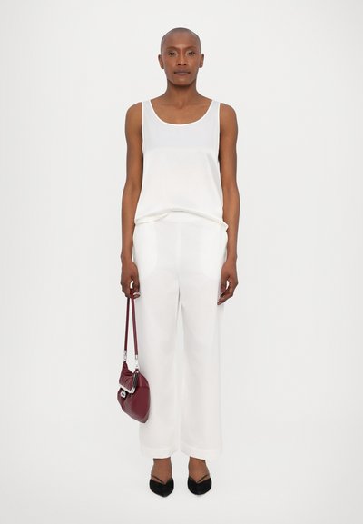 Valge aluspesu top ja kohandatud valged püksid, mida täiendab burgundia värvi käekott ja mustad terava ninaga madalad kingad. Sile kangas ja stiilne disain.