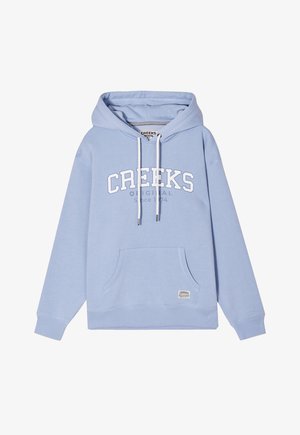 Felpa blu chiaro realizzata in tessuto morbido con tasca a marsupio frontale, cappuccio con cordino e testo stampato bianco che recita "CREEKS ORIGINAL Since 1974."