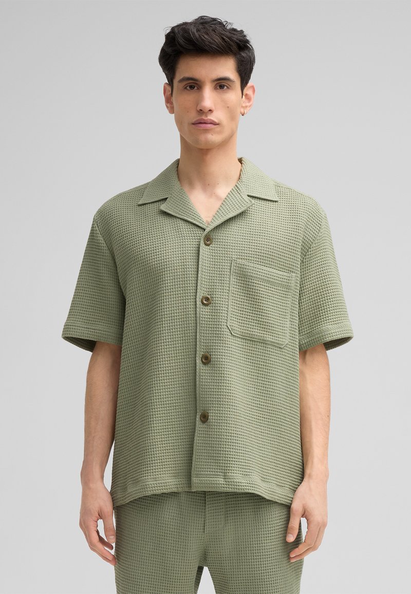 Korte mouw, knoopsluiting shirt in een gestructureerde lichtgroene stof, met een borstzak en bruine knopen. Gepaard met bijpassende broek.