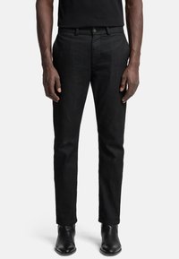 Zwarte denim broek met een slim fit, voorzien van een standaard tailleband, metalen knoop en ontworpen met een gladde textuur en minimale details.