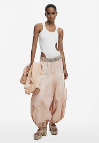 Valgete lõigatud tanktop, suured virsikuvärvi kandapüksid üle mõõdetud taskute ja vööga, sobiv virsikuvärvi jakk, beežid platvormkingad, sile kangas.