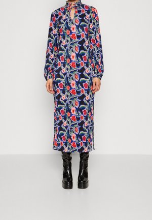 Vestido largo Floral con fondo marino, adornado con flores rojas y rosas, mangas largas y escote tipo ojal. Lleva botas negras brillantes.
