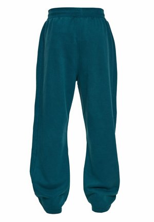 Tume-türkiissinised elastse vöökohaga spordipüksid elastsete äärte ja lõdva, lahtise lõikega.