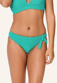 Tyrkysové bikiny s vysokým pásom maj�ú textúrovanú tkaninu a bočný uzol ako akcent. Hladký, elastický materiál a hravý detail.