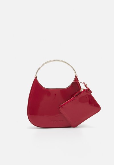 Red patent leather handbag with a curved shape, silver metal handle, and a matching removable pouch. Smooth texture, minimalist design.