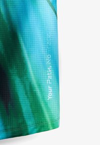 Korte mouwen blouse in een blauw-groen verloop, gemaakt van een getextureerd materiaal met rasteraccenten en bedrukt met tekstdetails.