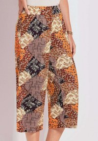 Culottes met een patchworkontwerp in oranje, bruin, crème en zwart met verschillende bloem- en geometrische patronen, gemaakt van lichtgewicht stof.