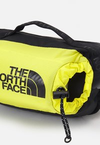 Torebka North Face z jasnoskalnym siateczkowym elementem, czarną tkaniną na dole, uchwytem oraz ściągaczem z plastikowym zatyczką.