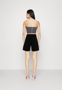 Grå strapless cropped top med vertikala sömmar, kombinerad med svarta shorts. Modellen bär rosa klacksandaler med blockklack.