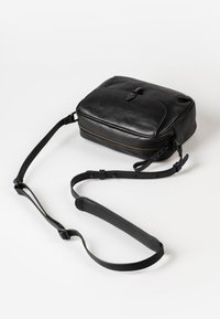 Borsa a tracolla in pelle nera con forma rettangolare, chiusura con zip e tracolla regolabile. Presenta una tasca frontale e una texture liscia.