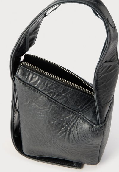 Μαύρη δερμάτινη τσάντα χειρός με ένα λουράκι και εμφανή ασημένιο φερμουάρ, που δείχνει τις υφές και τις ραφές σε απλό φόντο.