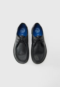 Black leather shoes with a textured finish, featuring two eyelets, thin laces, and a blue inner lining. Rounded toe design, minimalistic style.