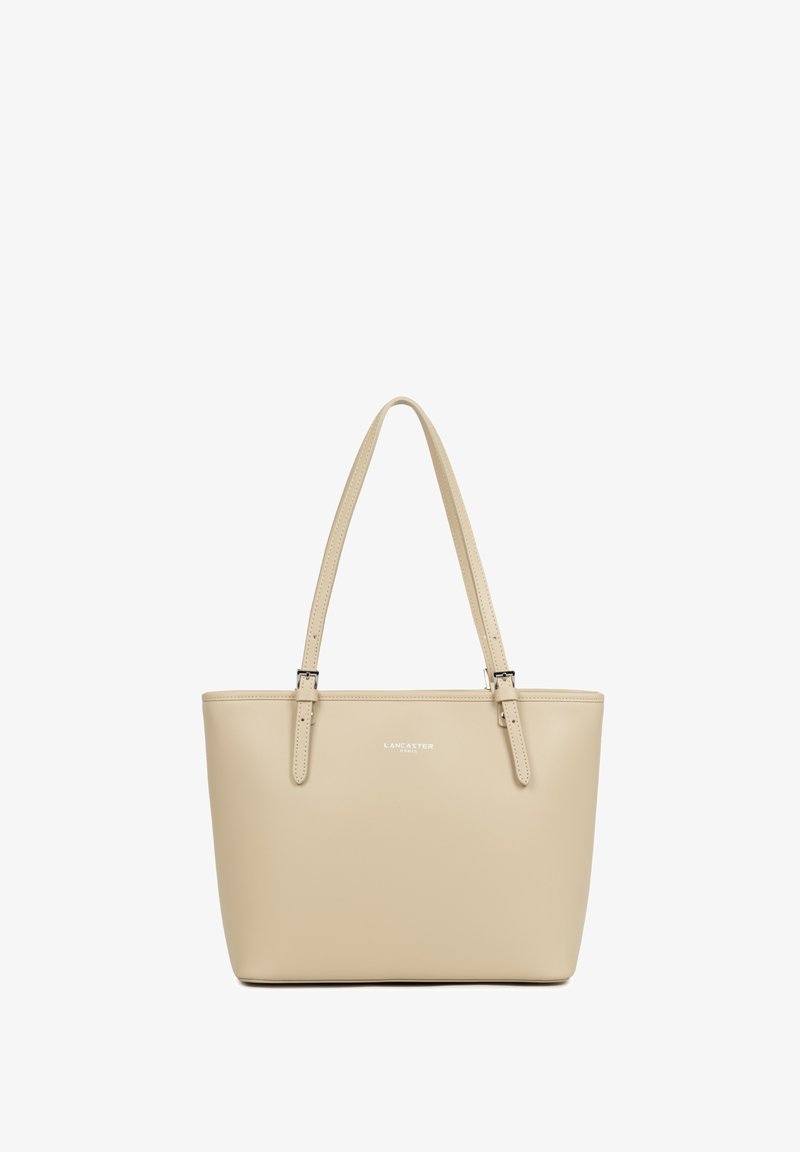 Sac fourre-tout en cuir beige avec deux sangles ajustables et petit logo argenté "Lancaster Paris" centré sur le devant.