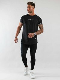 Svart T-shirt med vit text "LIMITÉ", svarta leggings och vita sneakers. T-shirten har mönstrade korta ärmar. Slät textur.