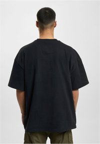 Black oversized t-shirt with short sleeves, crew neck, and soft cotton texture. Simple design with no patterns or graphics.