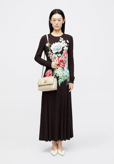 Μαύρο φόρεμα με μακριά μανίκια που διαθέτει πολύχρωμο floral σχέδιο; συνδυασμένο με μια τσάντα quilted σε μπεζ απόχρωση και λευκά παπούτσια με μυτερή μύτη.