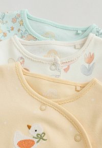Trois bodies pour bébé : un vert menthe avec motif floral, un crème avec imprimé animalier, et un jaune avec un canard brodé. Coton doux, col rond, fermeture boutons-pression.