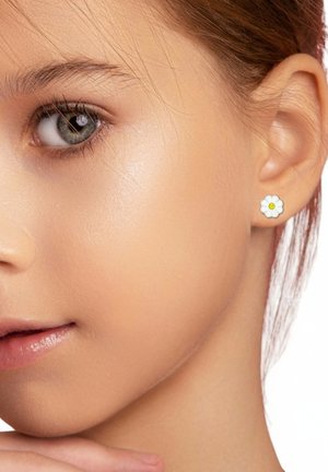 Weiße blütenförmige Ohrstecker mit gelbem Zentrum, aus Emaille gefertigt. Das Model hat glatte Haut und braune Haare und präsentiert die Ohrringe.