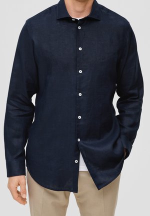 Camicia in lino blu navy con maniche lunghe, colletto a punta e bottoni bianchi. Vestibilità su misura con orlo curvo e una texture sottile.