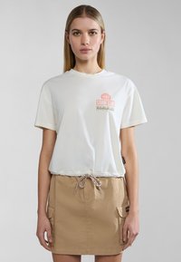 Lichtcrème t-shirt met ronde hals en korte mouwen, met een rood en grijs "Canoe Club" grafisch ontwerp; gecombineerd met een beige rok met zakken.