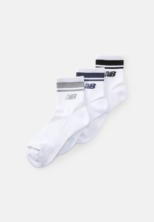 Drei Paar weiße Socken mit gerippten Bündchen, in Grau, Marineblau und Schwarz gestreift, jeweils mit dem New Balance-Logo versehen.