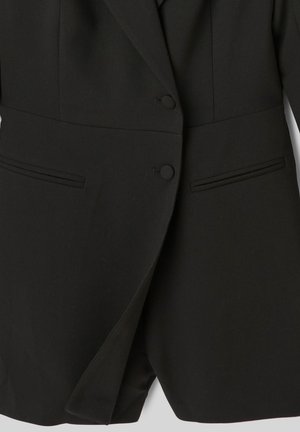Blazer noir avec une coupe ajustée, présentant deux boutons, des revers étroits et des poches latérales. Texture lisse avec un minimum de détails.