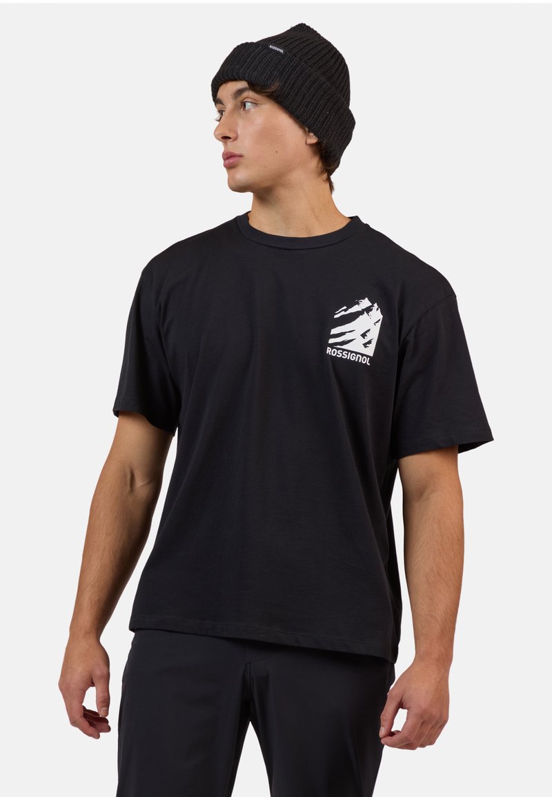 Černé bavlněné tričko s kulatým výstřihem a krátkými rukávy, se zlatým grafickým logem na levém hrudi. Vybaveno černou žebrovanou čepicí.
