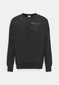 Sweatshirt noir Nike avec des manches raglan, des poches latérales zippées et un tissu texturé. Comprend un logo de la marque imprimé et des détails sur le devant.