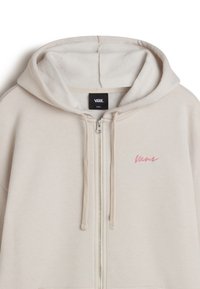 Beige Zip-up Hoodie aus weichem Stoff, mit einem pinken bestickten Logo auf der linken Brust und einer Kapuze mit Kordelzug.